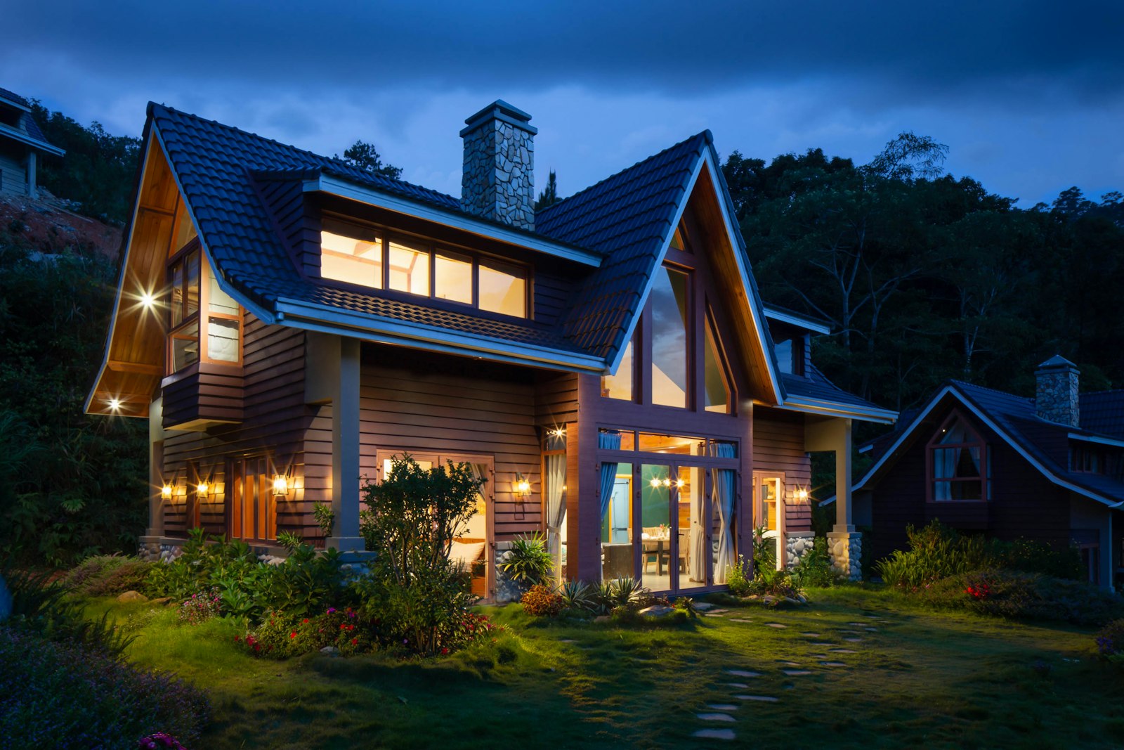 Warmly lit home with wood siding and stone accents on an evening hillside