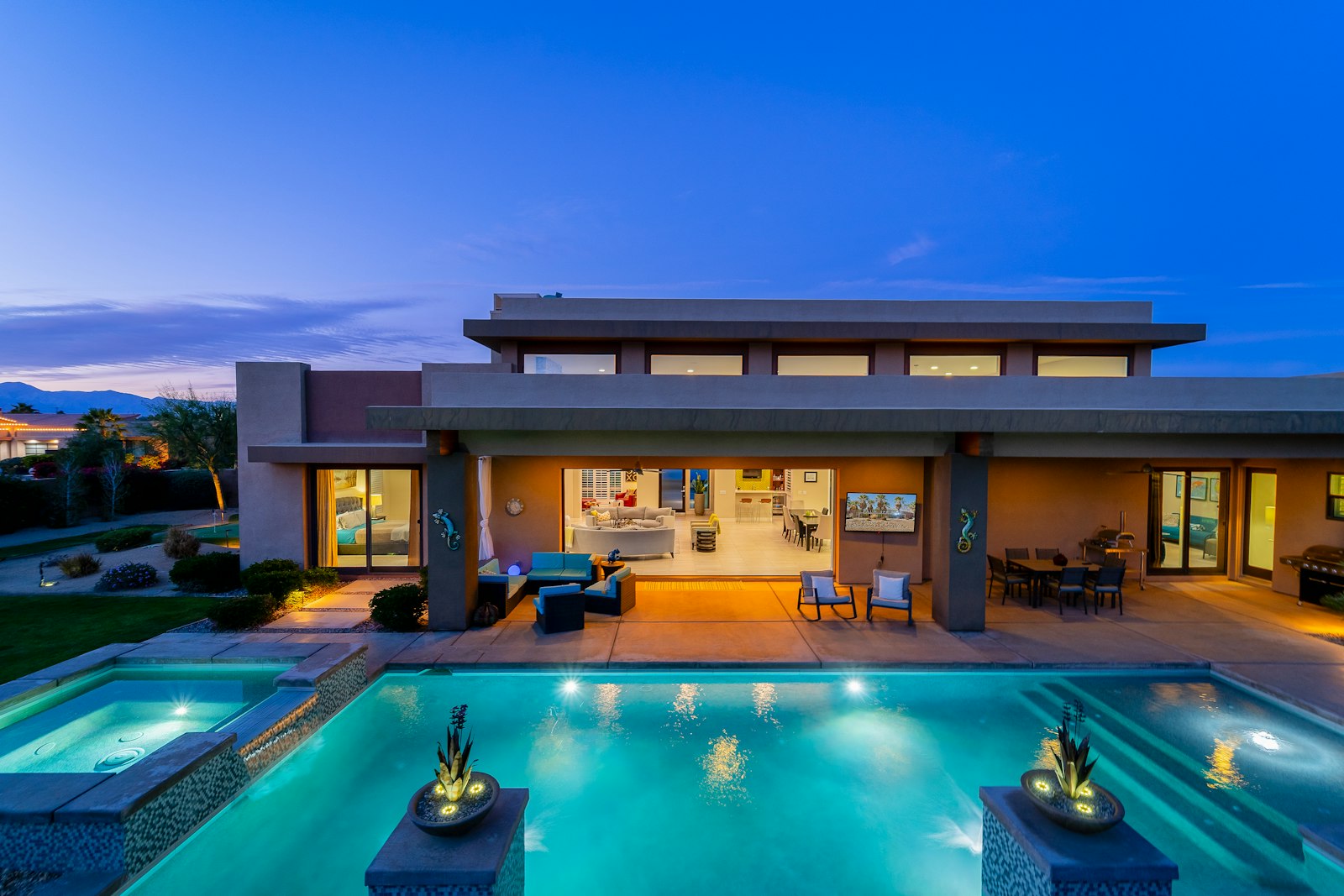Resort style backyard with a lit pool and clean patio at twilight