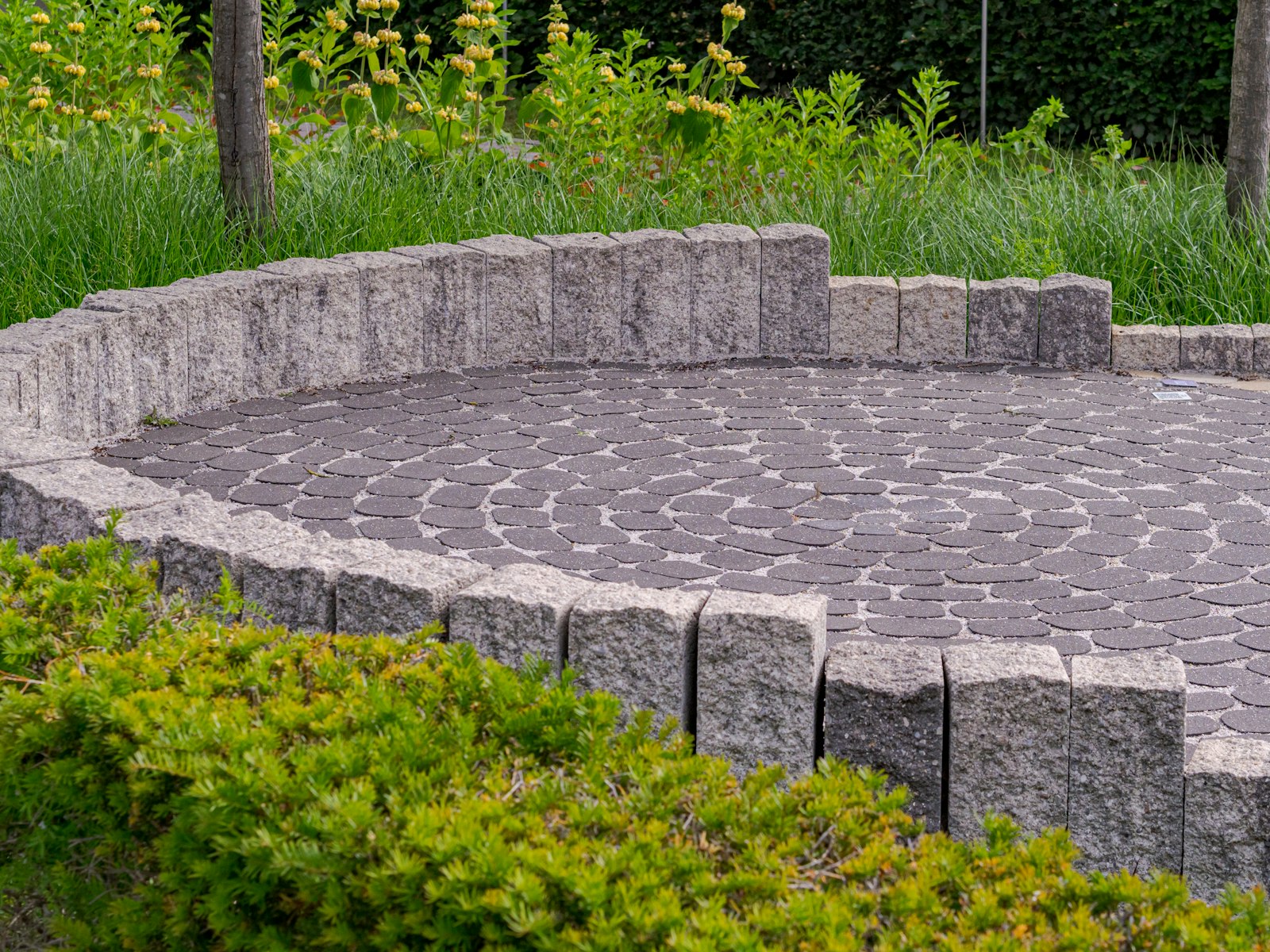 Circular paver patio with a stone seating wall, freshly cleaned with crisp joints