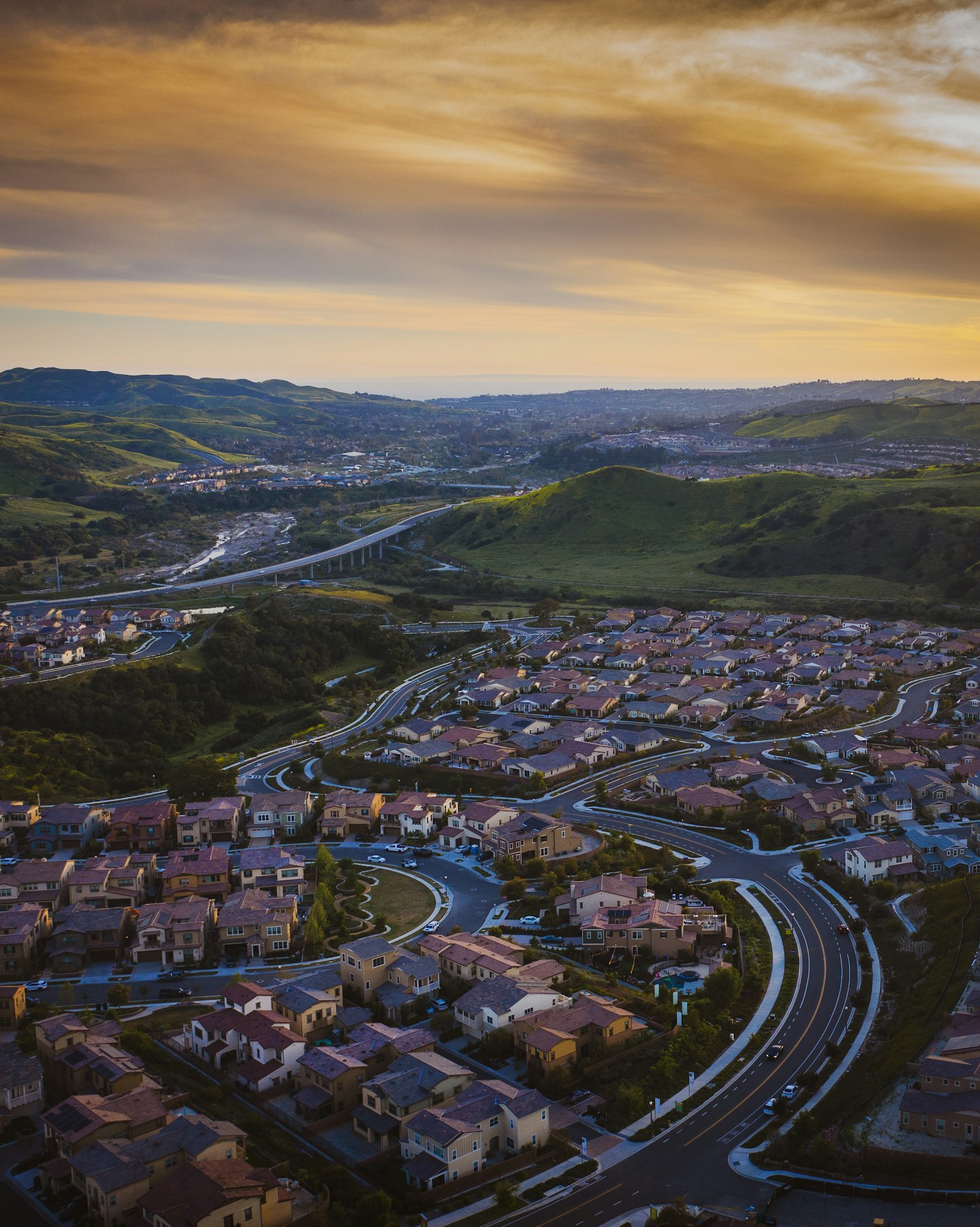 Golden hour aerial view of a Placer County neighborhood among rolling hills