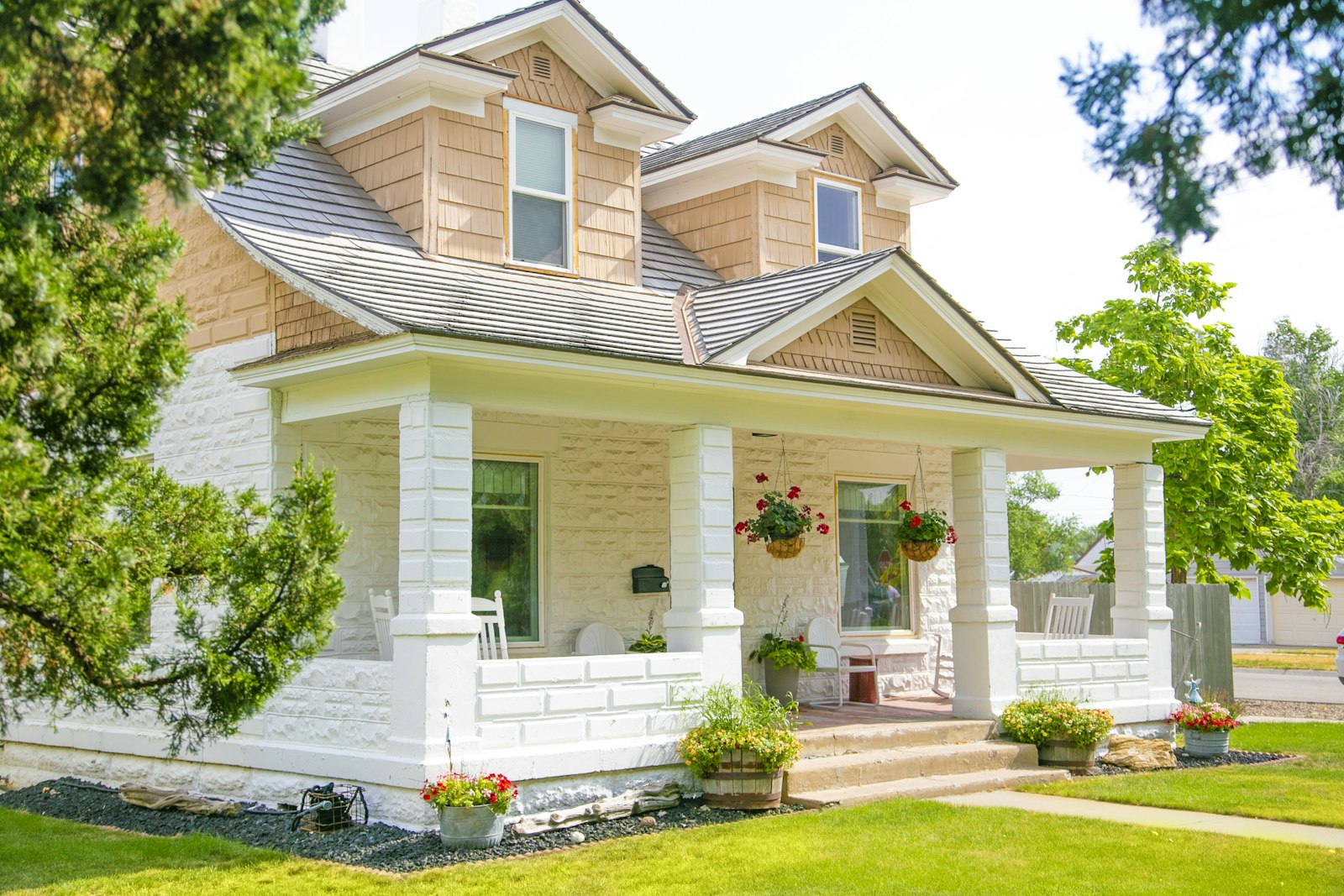 White craftsman front porch with hanging flower baskets and a spotless floor